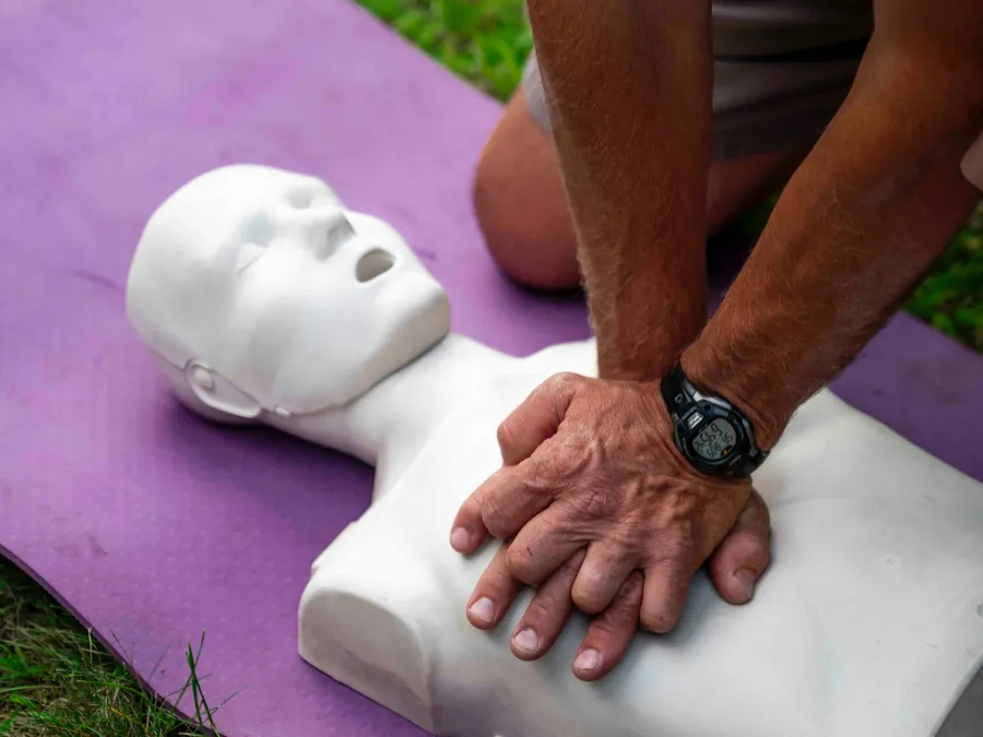 Eine Person übt die Herzdruckmassage an einer Übungspuppe